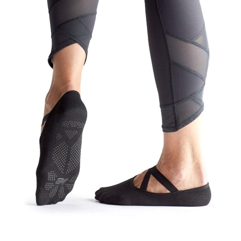 Woman's feet in black yoga socks and leggings, isolated on white