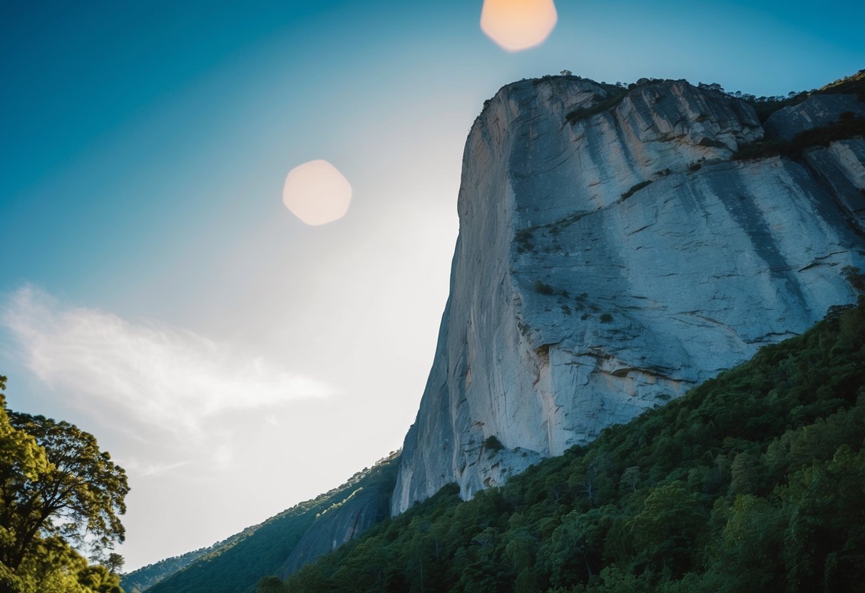 A towering rock face juts out against a backdrop of lush greenery, with climbers scaling its rugged surface against a clear blue sky